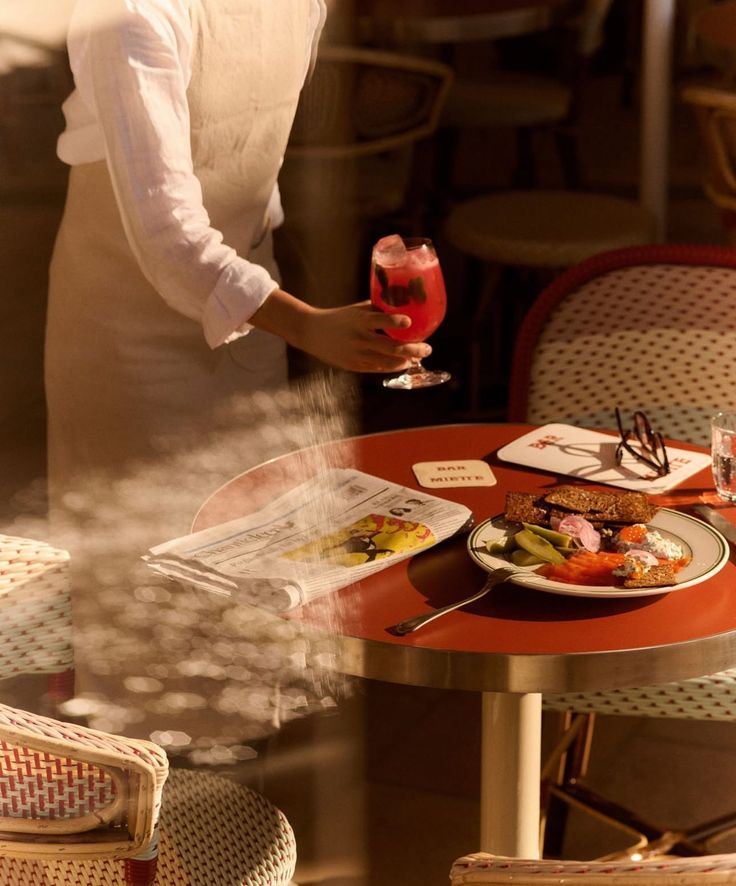 A server holding a drink beside a table set in warm light